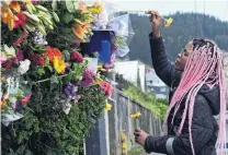  ?? PHOTO: LINDA ROBERTSON ?? Floral tribute . . . Tasha Gweshe (23), a student from a neighbouri­ng flat, places flowers in the hedge at the flat in Dundas St where Sophie Crestani died at a party on Saturday night.