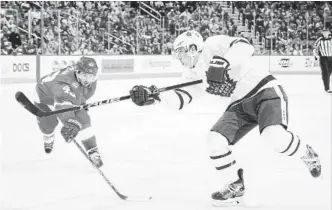  ?? DAVE REGINEK GETTY IMAGES ?? Maple Leafs’ Mitch Marner shoots the puck in front of Darren Helm of the Red Wings in Sunday’s game, won on a last-minute goal by Toronto’s Auston Matthews.