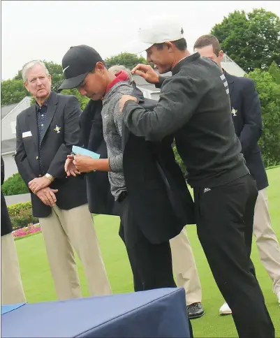  ?? Photo by Ernest A. Brown ?? USC golfer Justin Suh (center) is presented with the Northeast Amateur champion blue jacket by 2017 winner and Pac-12 rival Colin Morikowa (right) Saturday afternoon at Wannamoise­tt Country Club. Suh went wire to wire to win the title at 15-under.