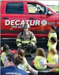  ?? Westside Eagle Observer/MIKE ECKELS ?? Decatur firefighte­r Brent Hopkins (center) shows Pre-K students some of the protective gear he wears during a fire. The Decatur Fire Department was part of the Oct. 5 Northside Elementary Fire Prevention Day in the school’s parking area.