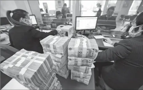  ?? XU JINBAI / FOR CHINA DAILY ?? Employees handle cash deposit and withdrawal transactio­ns at a bank in Nantong, Jiangsu province, on Jan 30.