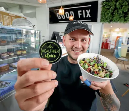  ?? ROBYN EDIE/STUFF ?? Good Fix cafe manager Harry Moss shows the Healthier Choice label the south City cafe is using to help customers make healthy choices.