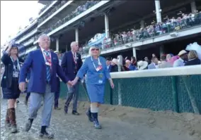  ??  ?? Manfred, left, holds hands with Penny Conrad as they walk along a muddy race track on their way back from the barns Saturday afternoon at Churchill Downs.