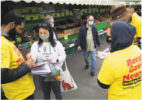  ?? Jessica Christian / The Chronicle ?? Volunteers with the Recall Gavin Newsom campaign, who declined to give their names, gather signatures in San Francisco.