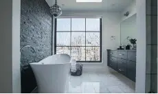  ??  ?? The master bathroom is a luxe retreat, with a large soaking tub and a window with frosted decals of branches. A pull-down shade offers privacy.