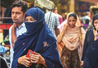  ?? PTI ?? A woman walks at a market near Jama Masjid, in New Delhi. Under the ordinance approved yesterday only a woman, or a close relative, can file a police case against her husband.