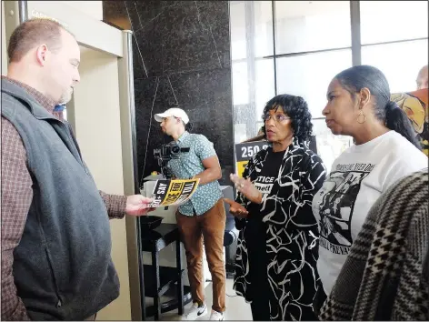  ?? (File Photo/AP/Rogelio V. Solis) ?? Deborah Watts (second from right), a cousin of Emmett Till — the Black 14-year-old from Chicago who was abducted, tortured and lynched after he allegedly whistled at a white woman in her family store in rural Mississipp­i — hands Mississipp­i Attorney General Office representa­tive Wayne Lynch a poster and accompanyi­ng thumb drive March 11 in Jackson, Miss. The thumb drive allegedly has almost 300,000 signatures on a petition seeking a renewed probe of the 1955 lynching.