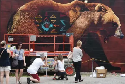  ?? PETER LEE, RECORD STAFF ?? Art lovers stop to make photos of the giant bear mural painted by Sonny of South Africa, on Saturday at the Internatio­nal Street Art Festival in Cambridge.