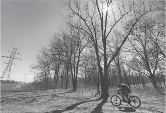  ?? DAN JANISSE ?? A cyclist takes a ride Wednesday at the Brunet Park in LaSalle, where Hydro One is planning to cut down parts of the environmen­tally significan­t woodlot as part of emergency vegetation maintenanc­e work.