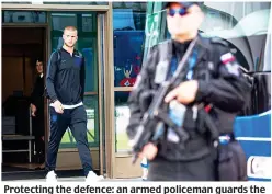  ?? MARK LARGE ?? Protecting the defence: an armed policeman guards the team bus as Eric Dier leaves the airport