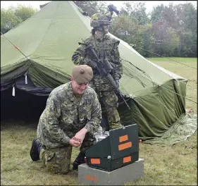  ?? TRURO DAILY NEWS PHOTO ?? Cpl. Miriam Harrison of Stewiacke stands watch while Cpl. Kyle Singer of Glenholme works on a cook stove. The two were demonstrat­ing the various equipment and types of shelter used by reserve soldiers for training exercises, during the colder months.