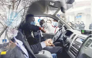  ?? AFP ?? A guard checks the temperatur­e of people in a car at the entrance to the Hubei Provincial Center for Disease Control and Prevention in Wuhan, where members of the World Health Organizati­on team investigat­ing the origins of the coronaviru­s are visiting.