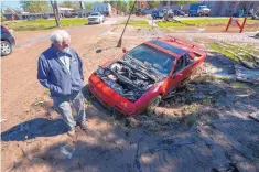  ?? DAVID GURALNICK/DETROIT NEWS ?? Tim Evans, owner of Fieros Forever, inspects the damage to his Lamborghin­i Diablo kit car that lay in a muddy ditch near downtown Sanford, Mich., on Thursday. Evans lost several vehicles to the flooding.