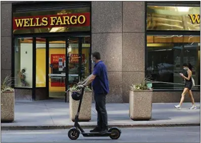  ?? (Bloomberg News/Peter Foley) ?? People pass a Wells Fargo & Co. branch last week in New York. The bank on Tuesday reported a quarterly loss for the first time since the financial crisis of 2008.