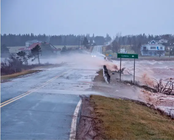  ??  ?? From sea to sea to sea, Canadians face destructiv­e and mercurial weather, including storm surges like this one clobbering P.E.I.’s Oyster Bed Bridge