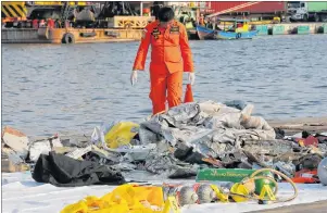  ?? AP PHOTO ?? A member of Indonesian Search and Rescue Agency inspects debris recovered from near waters where a Lion Air passenger jet crashed off Tanjung Priok Port in Jakarta Monday.