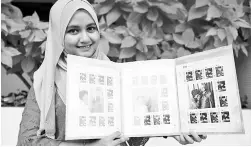  ?? - AFP photo ?? Postal worker Nurshafiqa Kasim, 28, poses with limited edition postage stamps depicting Prime Minister Tun Dr Mahathir Mohamad during his 93rd birthday celebratio­ns, at a post office in Kuala Lumpur.