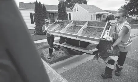  ?? DAX MELMER ?? Kyle Marchand, left, and Spencer Brown from Miller Waste Systems toss a couch that was damaged in the flood into the back of their garbage truck as they pick up debris along Forest Avenue. Their truck was just one of 10 dedicated to removing flood...