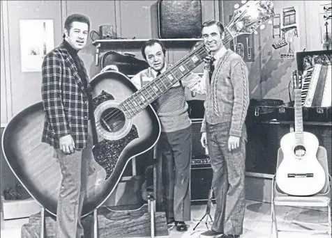  ?? Above and below left, courtesy of Joe Negri ?? Joe Negri, center, with fellow jazz guitarist Kenny Burrell, left, and Fred Rogers on the set of “Mister Rogers Neighborho­od” in 1975.