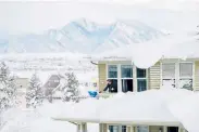  ?? Meghan Lyden, Special to The Denver Post ?? Andrew Thorne cleans snow off of his porch roof from the second-floor window of his Arvada home on Monday.