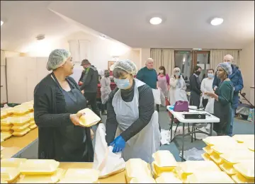  ??  ?? Andrew (right) talks to volunteer Diane Proctor (foreground left) as members of the Preston Windrush Covid Response team dish out West Indian meals at the Xaverian Sanctuary.