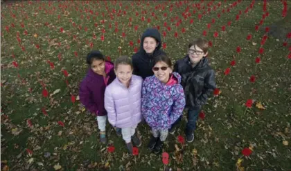  ?? RECORD STAFF ?? Breslau Public School students, from left, Tanish Randhawa, Shaelin Muller, Danika Tanev, Ashton Wallace and Owen Hopkins stand among handmade poppies in front of the school on Tuesday.