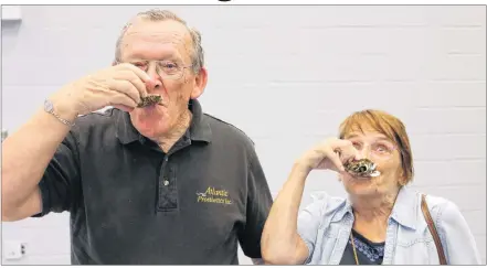  ?? MILLICENT MCKAY/JOURNAL PIONEER ?? Father Eddie Cormier, left, and Marie Arsenault enjoy traditiona­l Acadian treats at the recent announceme­nt for the Congrès Mondial Acadien.