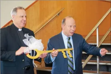  ?? MARIAN DENNIS – DIGITAL FIRST MEDIA ?? Monsignor Joseph Marino (left) and Jerry Parsons prepare to hand the key to the school over to its new owners. The school building at 844 Keim Street will be the new location for St. Aloysius Parish School, currently located at Beech and North Hanover...