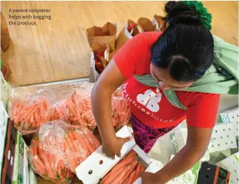  ??  ?? A parent volunteer helps with bagging the produce.