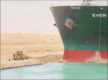  ?? Associated Press ?? The Ever Given sits with its bow stuck into a wall Wednesday, after it become wedged across Egypt’s Suez Canal and blocked all traffic in the vital waterway.