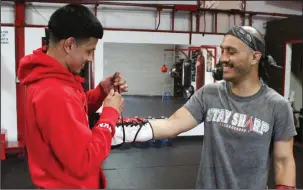  ?? MIKE BUSH/NEWS-SENTINEL ?? Giovannie Gonzalez (right) gets help putting on his boxing gloves from Marco Arroyo at East Stockton Boxing Club on May 3. Today, the Tokay High grad will have a boxing match in Stockton.