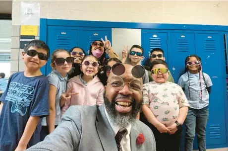  ?? COURTESY/BALTIMORE SUN ?? Fallstaff Elementary/Middle School Principal Sedrick Smith poses with a group of second graders on “sunglasses day.”