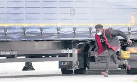  ?? CHRISTOPHE ENA/AP ?? A migrant runs alongside a truck this month in Calais, France, in an effort to stowaway on the vehicle for a ride through the tunnel to Britain.