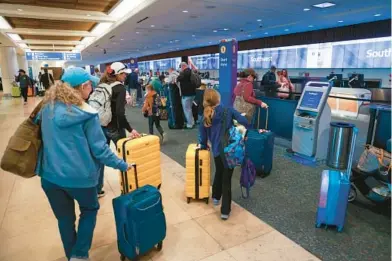  ?? RICH POPE/ORLANDO SENTINEL ?? Southwest Airlines passengers arrive at the airline’s kiosks at Terminal A of Orlando Internatio­nal Airport. Southwest has long been the busiest airline at Orlando and plans to boost flight numbers to record levels in the spring.