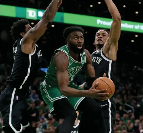  ?? MATT sTone / HerAld sTAff ?? SPLIT THE DIFFERENCE: Jaylen Brown converts a reverse lay-up between Brooklyn’s Kyrie Irving and Nic Claxton during a 114-107 Celtics’ win in Game 2 of their first-round series with the Nets on Wednesday night at TD Garden.