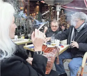  ?? 2008 PHOTO BY REMY DE LA MAUVINIERE/AP ?? Tourists enjoy a cigarette at a cafe-restaurant on the Champs Elysees in Paris after France pushed all smoking outside.