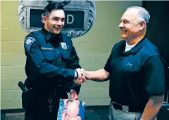  ?? SOUTH BEND POLICE DEPARTMENT VIA THE NEW YORK TIMES ?? South Bend police officer Matthew Hegedus-Stewart, left, and retired South Bend Police Lt. Gene Eyster during their first meeting at the South Bend Police Department earlier this year. Hegedus-Stewart is holding a picture of himself from Dec. 22, 2000, the day he was abandoned at 2 days old.