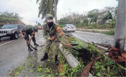  ?? PEDRO PARDO/AFP VIA GETTY IMAGES ?? Members of the Mexican Army remove fallen trees in Cancun, Mexico, on Wednesday.