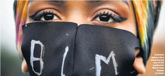  ??  ?? > A woman wears a face mask during one of the weekend’s Black Lives Matter protests