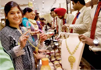  ?? PTI ?? A woman tries a gold necklace in a shop on the occasion of Akshaya Tritiya in New Delhi on Friday. —