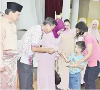  ??  ?? (Gambar atas) ASSAFAL dan isteri menyampaik­an duit raya kepada salah seorang kanak-kanak pada majlis itu. (Gambar kiri) HIDANGAN kambing bakar yang disediakan di salah sebuah gerai jabatan.