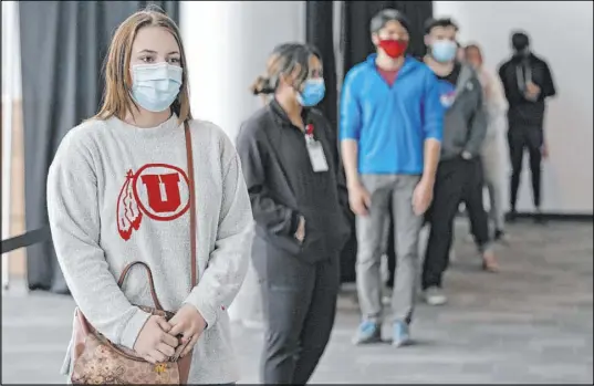  ?? Rick Bowmer The Associated Press ?? University of Utah student Abigail Shull waits in line Wednesday before taking a rapid COVID-19 test at the university’s student testing site in Salt Lake City. Thousands of cases have been connected to campuses since some colleges reopened.