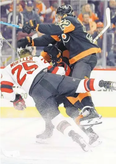  ?? PHOTO BY AP ?? Devils' Mirco Mueller is knocked off his skates by Dale Weise on Saturday in Philadelph­ia.