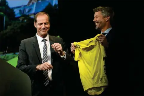  ?? ?? Kronprins Frederik fik overrakt en gave til sønnen Christian i form af gul førertrøje fra Tour de France-direktør Christian Prudhomme. Foto: Anne-Christine Poujoulat/AFP