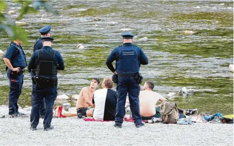  ?? Fotos: Annette Zoepf ?? Am Lech grillen drei Männer Würstel. Unter dem Blick des Ordnungsdi­enstes müssen sie die Glut löschen.