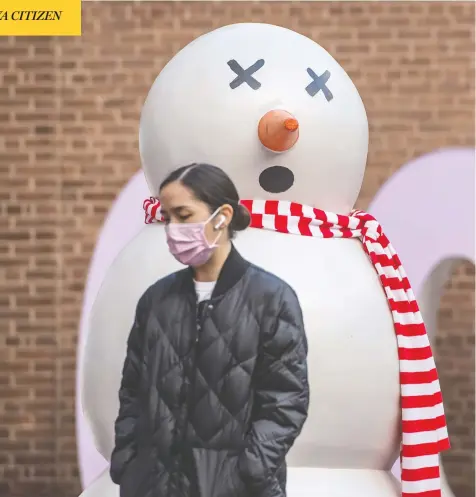  ?? PETER J THOMPSON / POSTMEDIA NEWS ?? A pedestrian walks past a snowman in Toronto on Thursday, as COVID restrictio­ns across Canada are changing how the holidays are observed.