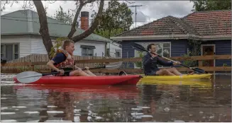  ?? ?? Residents in the suburb of Maribyrnon­g canoe down a flooded street