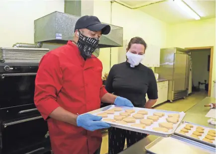  ?? MICHAEL SEARS / MILWAUKEE JOURNAL SENTINEL ?? Alan Goodman of A Goodman’s Desserts bakes a batch of Good Butter Cookies for a farewell gathering onsite at Redeemer Lutheran Church in Milwaukee. Goodman shows the cookies to the Rev. Lisa Bates-Froiland, host of the party, before they go into the oven.