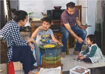  ?? New York Times ?? Akanksha Chadda and her husband, Ashish Anand, with their children at home in Noida, India. The family is struggling to stay afloat after the pandemic left the couple without jobs.