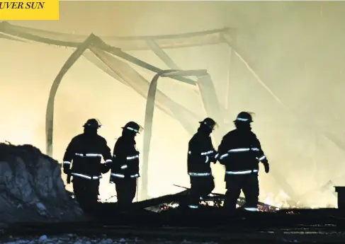  ?? SAMANTHA KEARLEY ?? Firefighte­rs walk through the wreckage of the lone elementary school in the small community of Milltown-Bay d’Espoir, N.L., where three fires had been set in sequence early Tuesday. The town hall and RCMP detachment were also set ablaze.